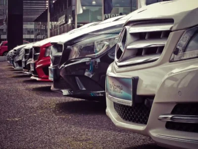 Três carros esportivos de alta performance estacionados em uma pista ao entardecer, destacando-se pelo design moderno e rodas esportivas.