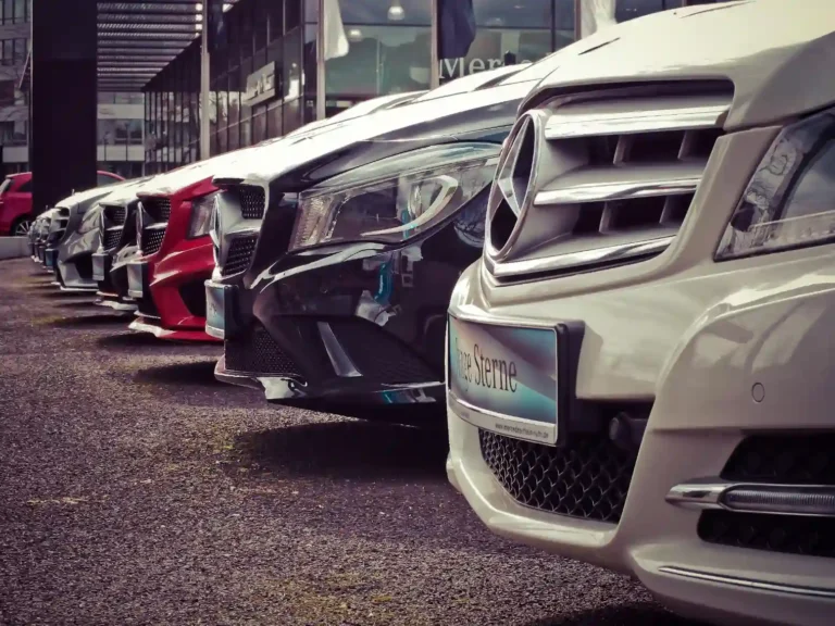Três carros esportivos de alta performance estacionados em uma pista ao entardecer, destacando-se pelo design moderno e rodas esportivas.